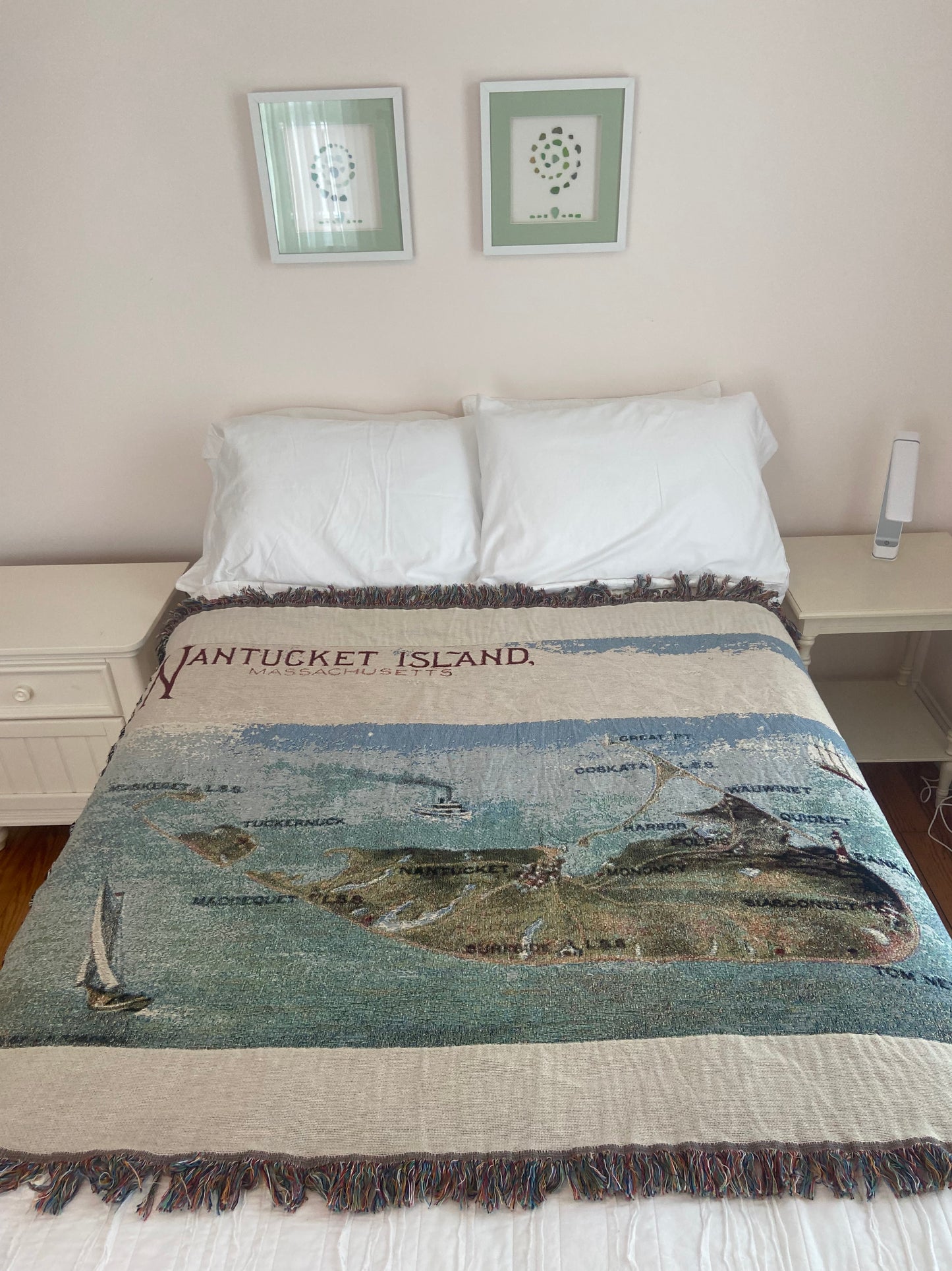 Blanket with 'Nantucket Island' text draped over a bed in a room.