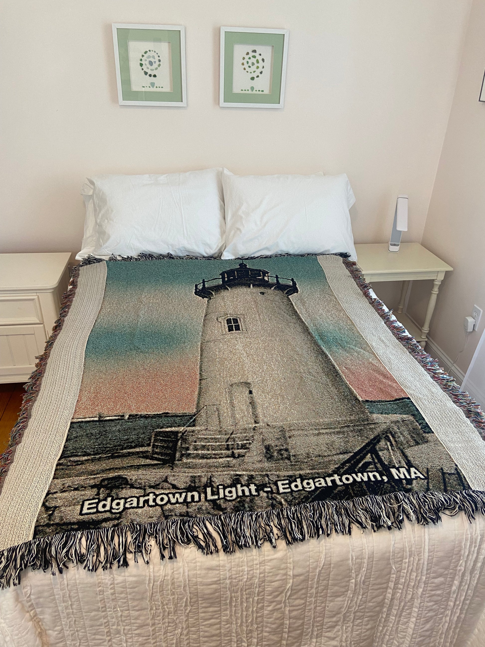 Textile with a printed design of a lighthouse on a bed in a room.