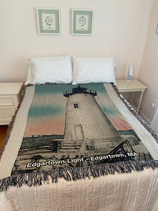 Textile with a printed design of a lighthouse on a bed in a room.