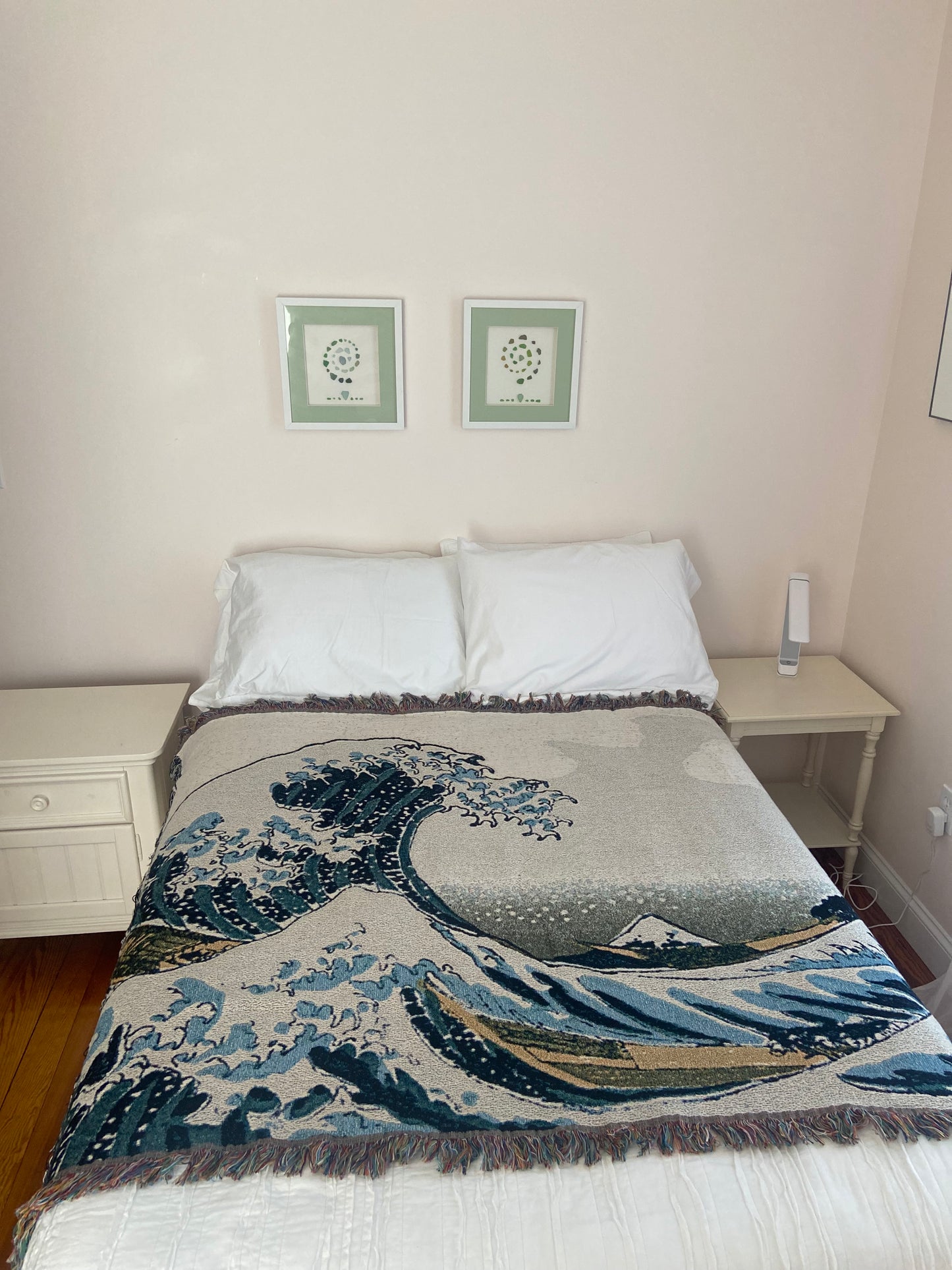 Bed with decorative blanket and pillows in a room with framed pictures on the wall.